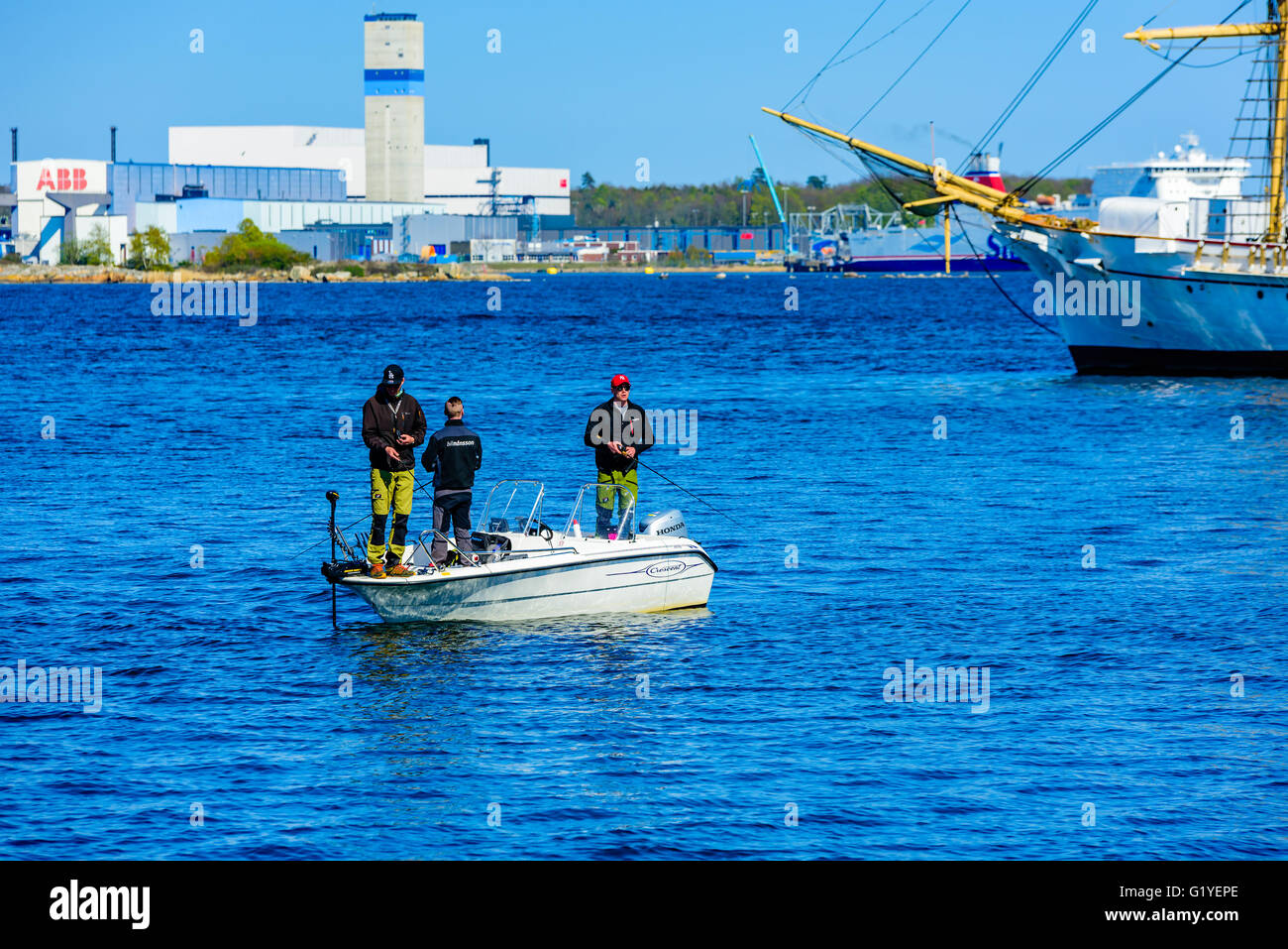Karlskrona, Suède - mai 5, 2016 : trois jeunes hommes adultes debout dans un bateau à moteur de croissant avec la tige et s'attaquer à la pêche. Vieux bateau à s Banque D'Images