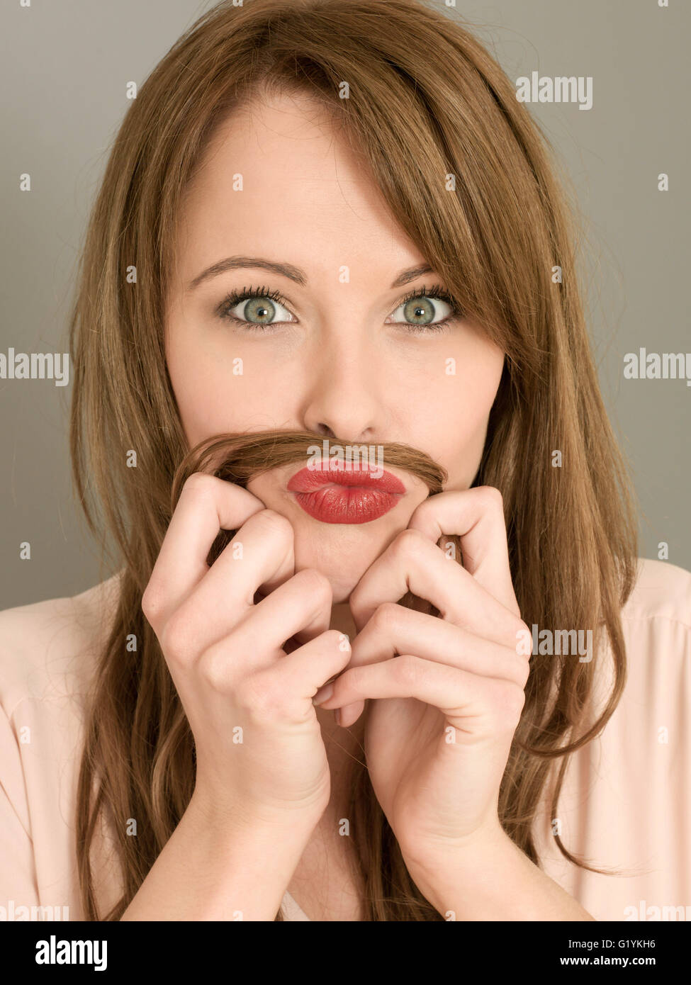 Portrait d'une femme d'être drôle et humoristique tirant ses cheveux sur sa lèvre supérieure pour faire une moustache avec un bête express ludique Banque D'Images