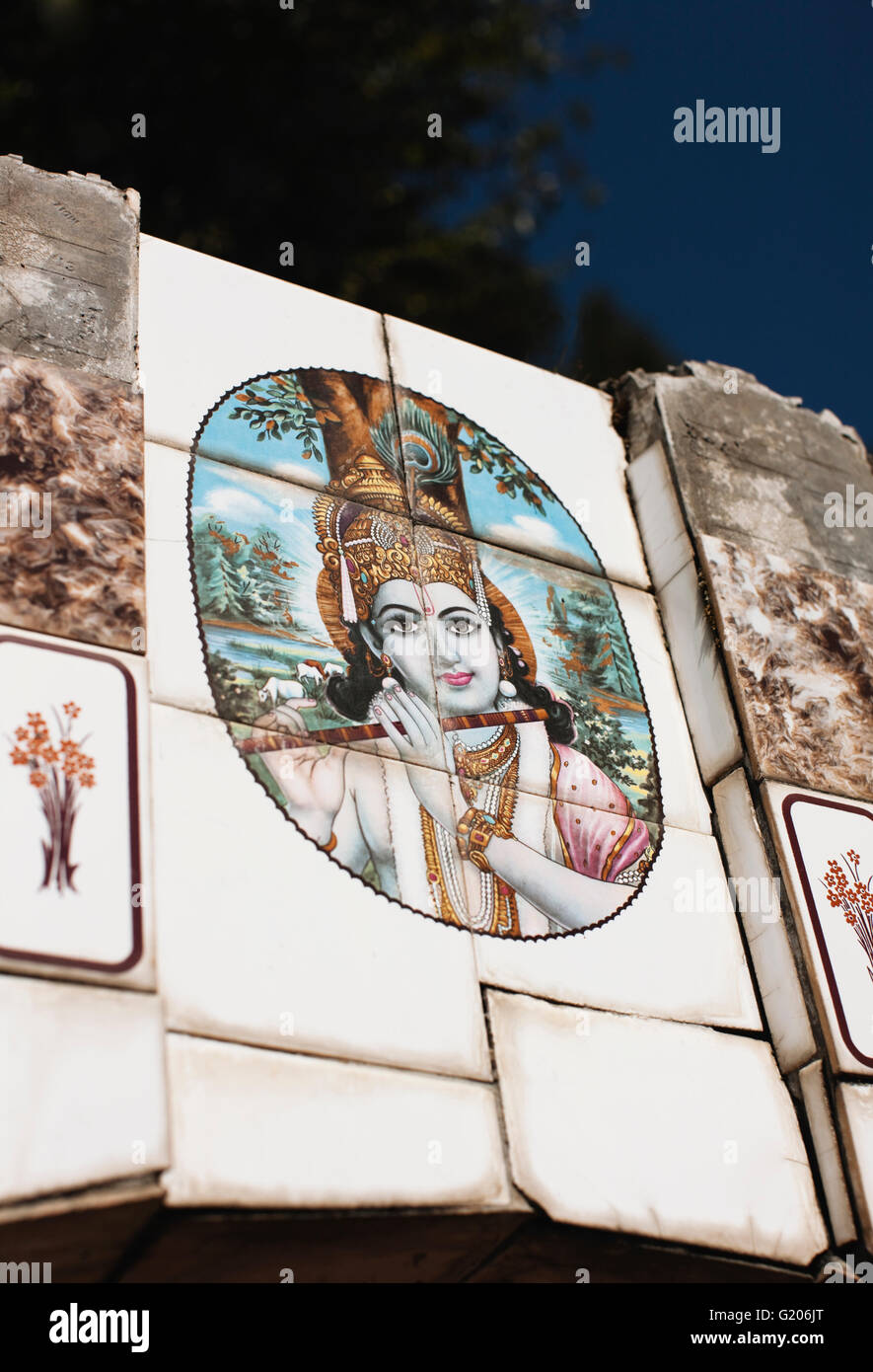 Iconographie du dieu hindou Krishna jouant de la flûte orne une route bien l'eau à McLeod Ganj, Dharamsala, Inde. Banque D'Images