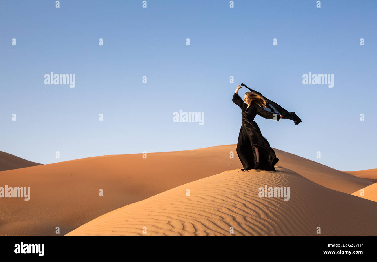 Une femme en abaya dans sanddunes dans Liwa Desert, Aby Dhabi, EAU Banque D'Images