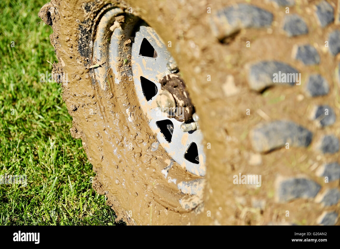 Gros véhicule off road pneu et roue pleine de boue sur l'herbe verte Banque D'Images