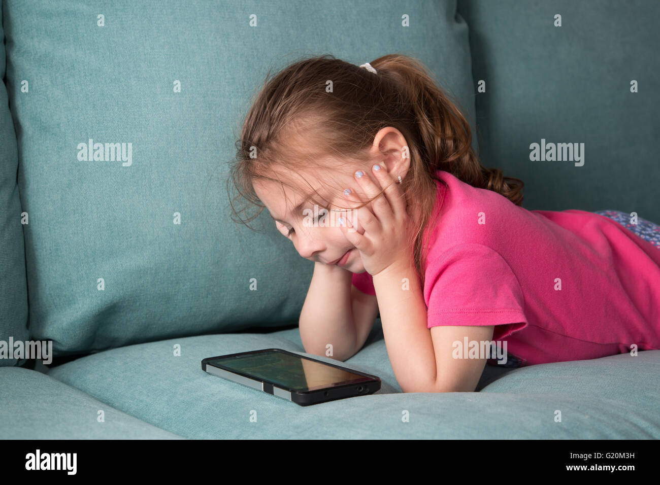 Tout-petit jouer aux jeux sur un téléphone cellulaire. Banque D'Images