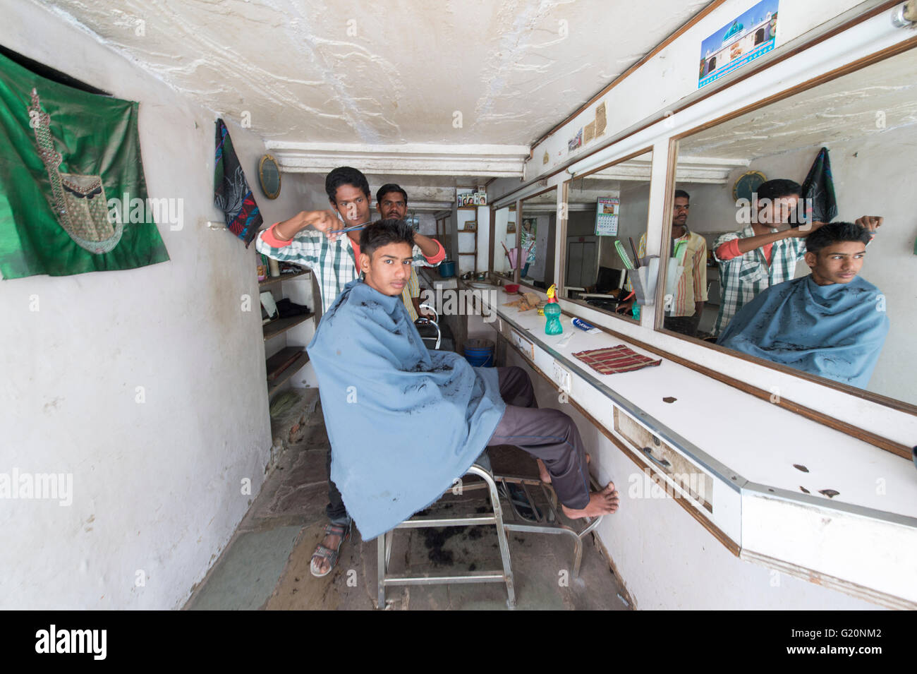 Un Indien posent pour l'appareil photo à l'intérieur de la boutique de coiffeur dans la rue de la ville d'Ajmer, Inde. Banque D'Images
