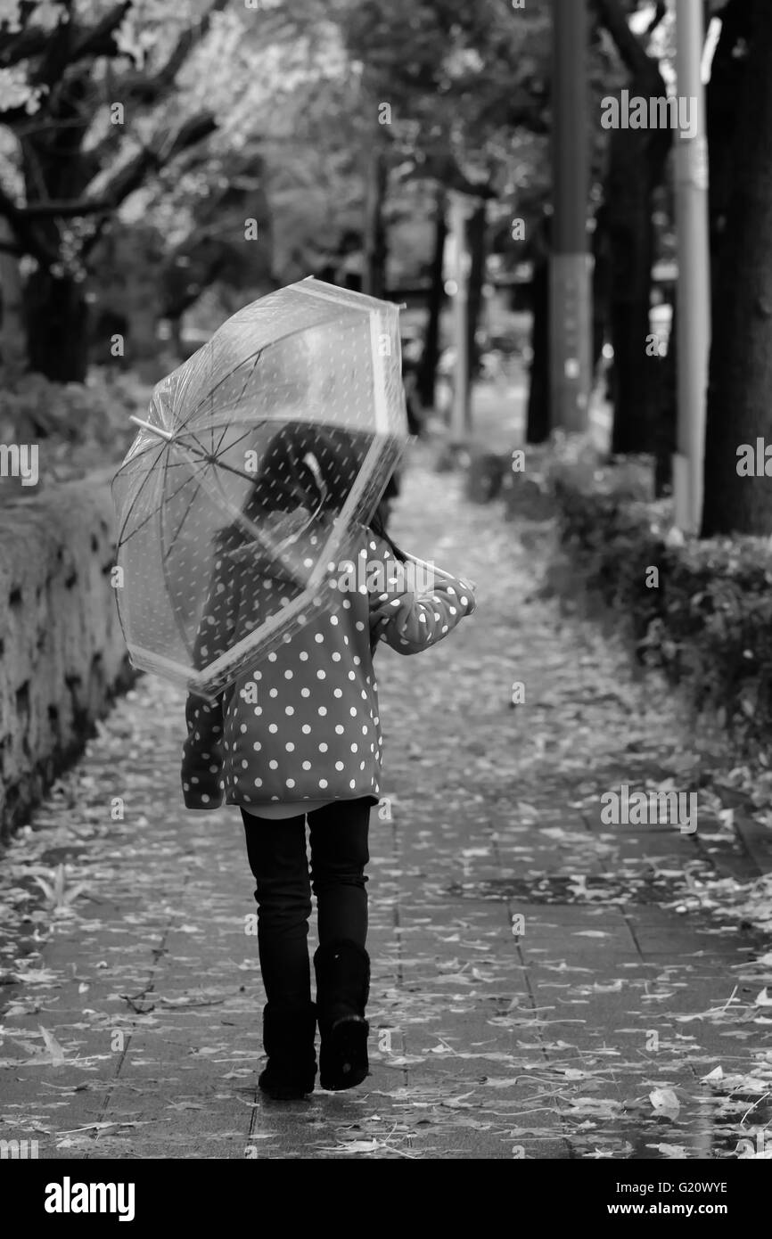 Fille de marcher seul avec parapluie Banque D'Images