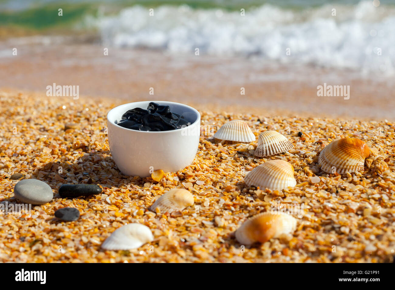 Boue de la mer morte pour les soins spa dans une tasse sur la plage Banque D'Images