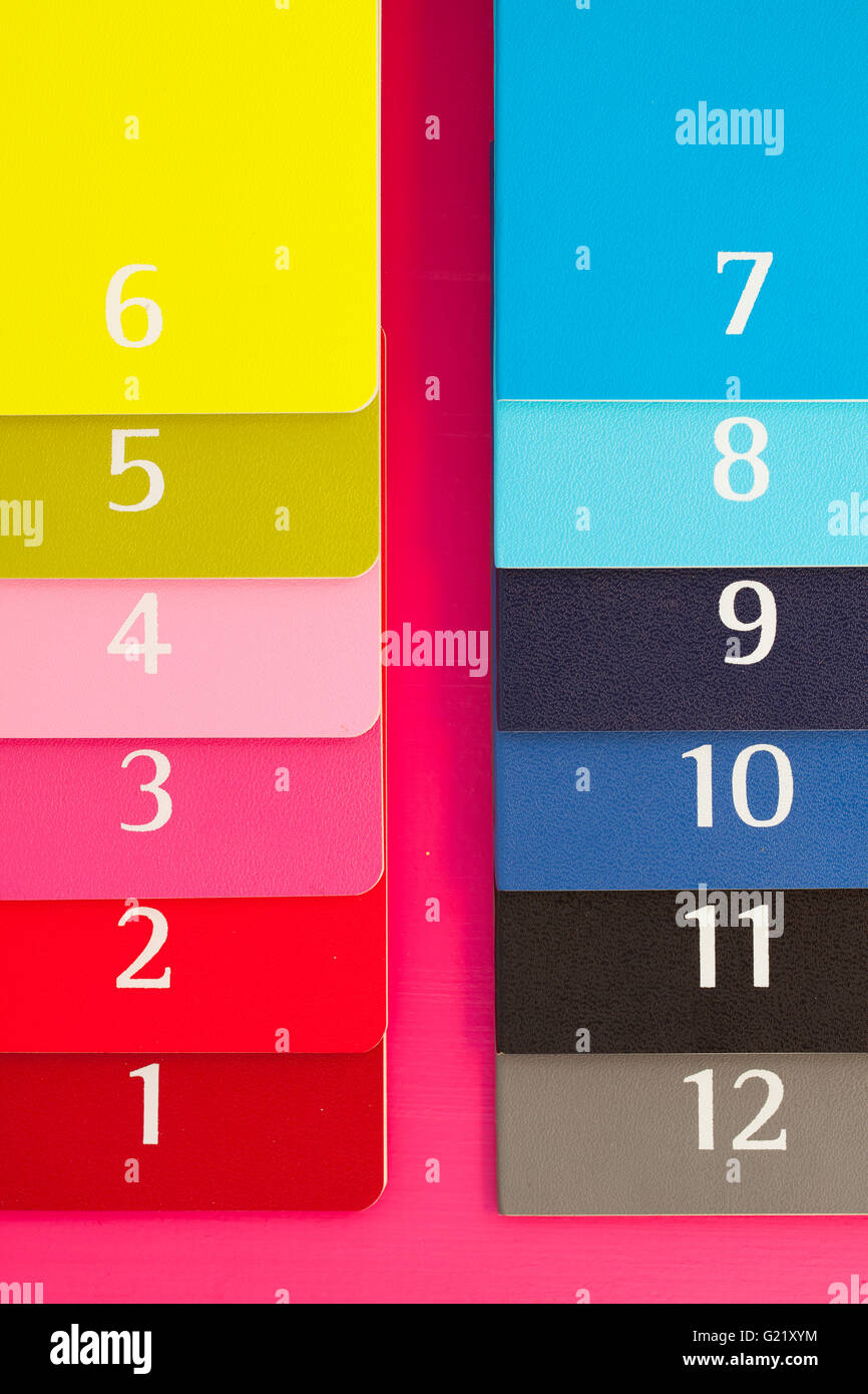 Douze journaux de couleur différente sur une table en bois de rose Banque D'Images