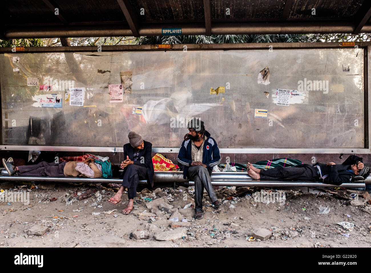 Quatre personnes ou de dormir assis à un arrêt de bus à Delhi, en Inde. Banque D'Images