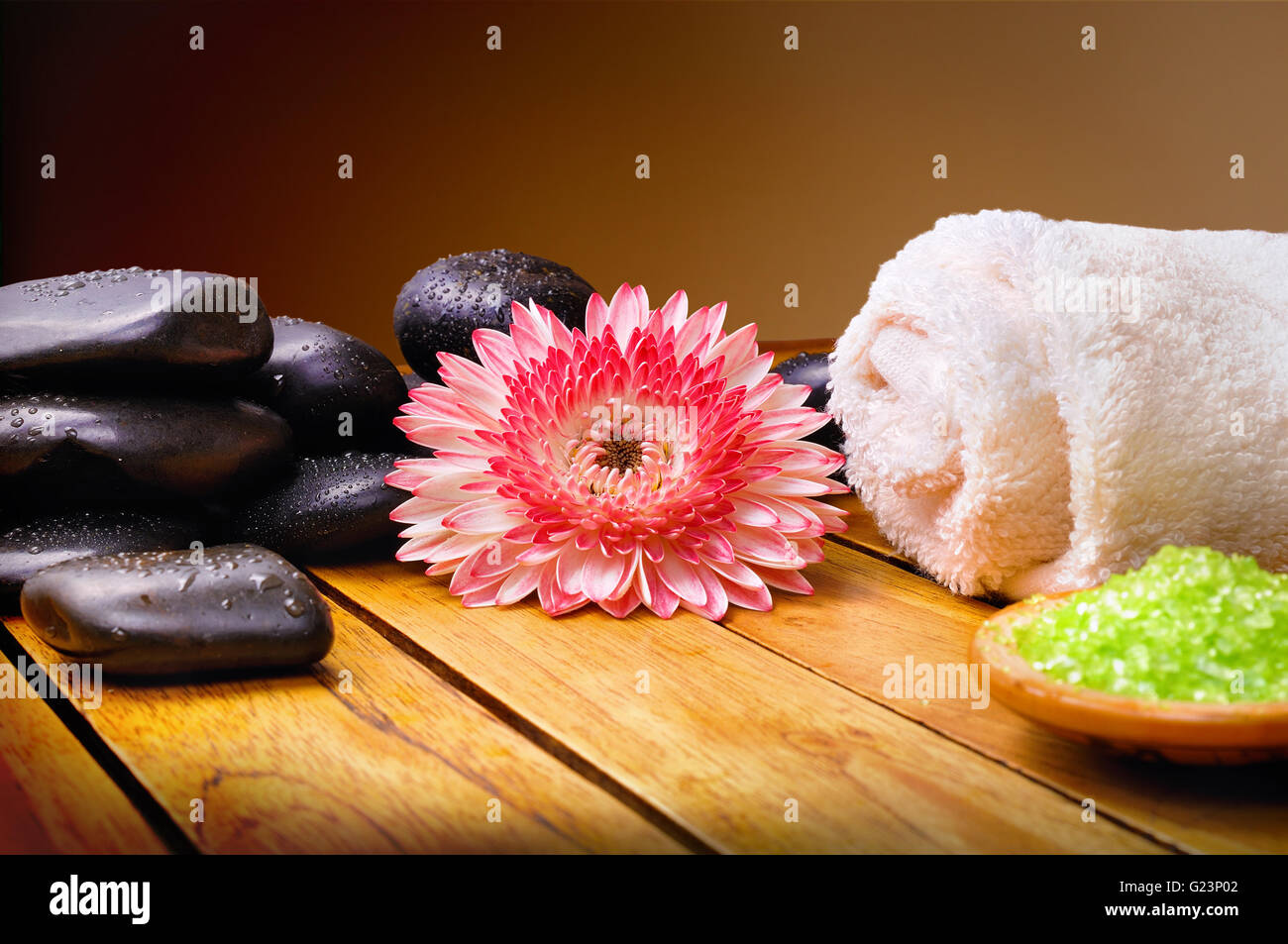 Les pierres noires, fleur, serviette et sels de bain sur des lattes de bois. Brown background. Composition horizontale Banque D'Images