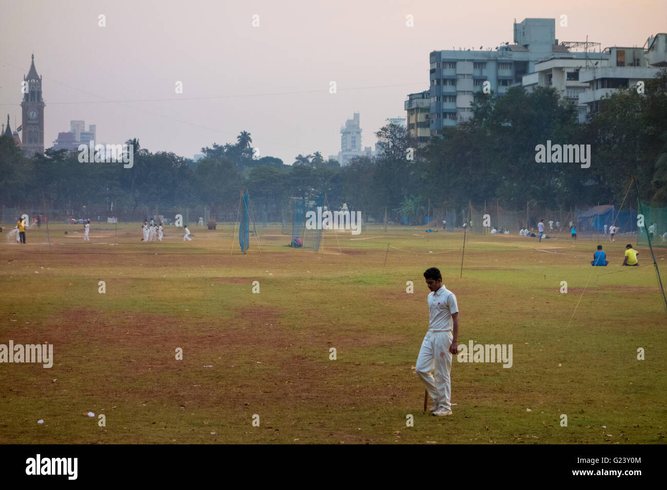 Un garçon marche dans ses atours de cricket à travers un parc à Mumbai, Inde Banque D'Images