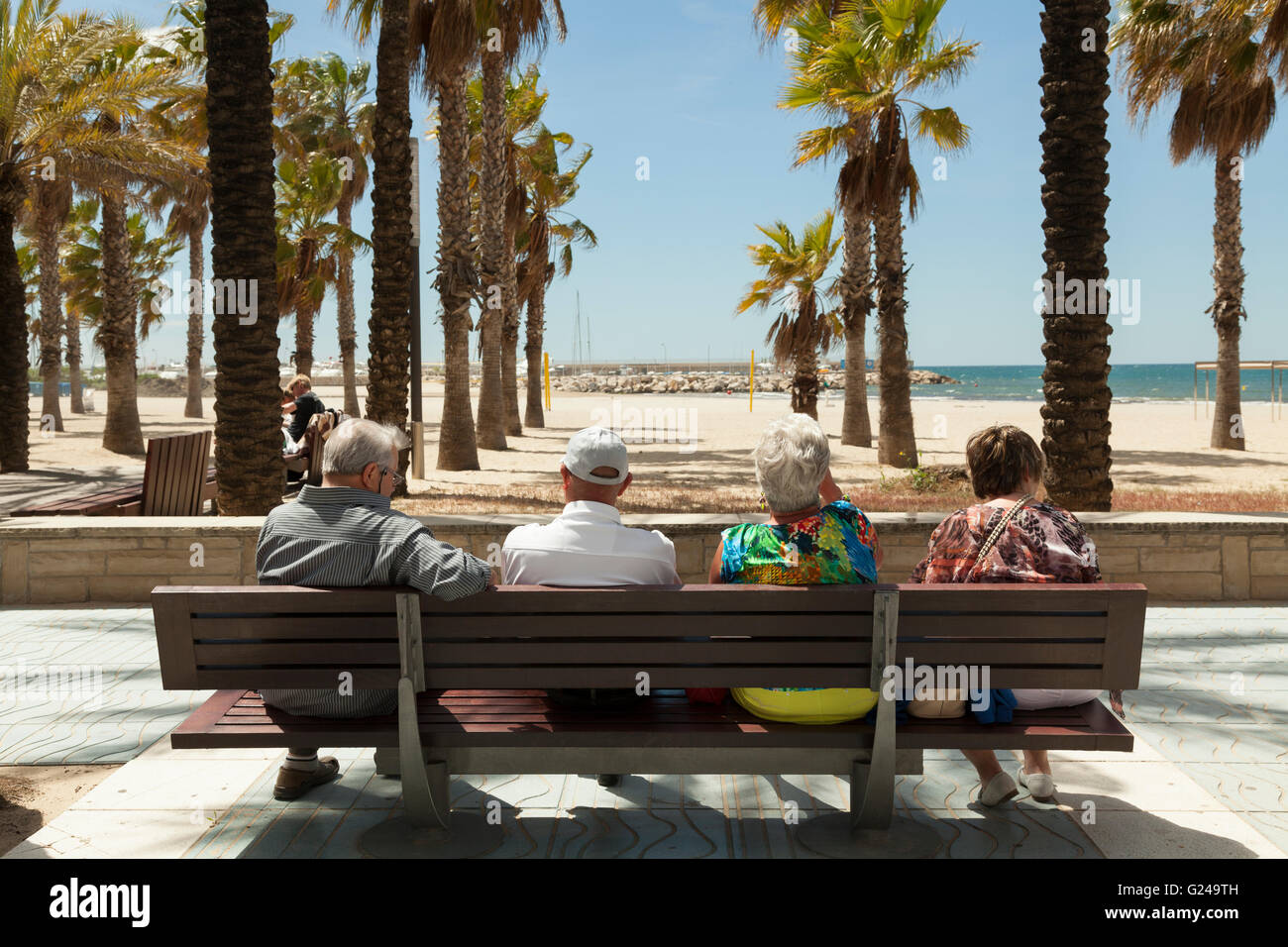 Vue arrière de l'appui sur les touristes à la recherche de banquette à palmier plage couverte, Salou, Catalogne, Espagne Banque D'Images