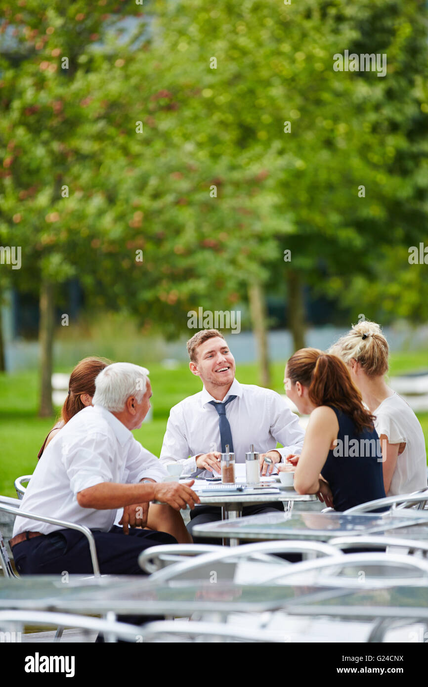 L'équipe d'avoir une réunion à l'extérieur dans un restaurant en été Banque D'Images