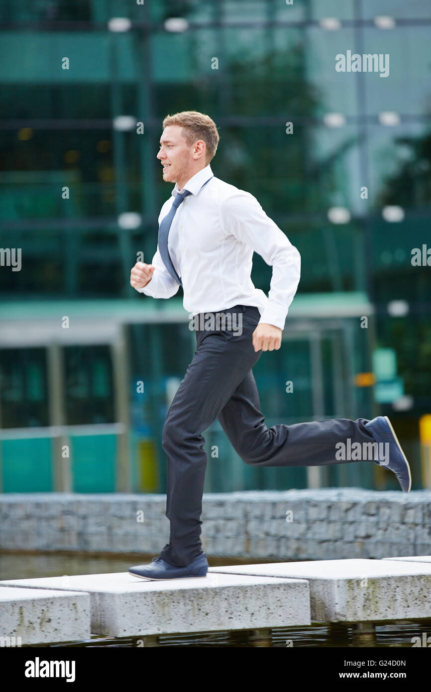 Jeune homme d'affaires actif courir devant son bureau Banque D'Images