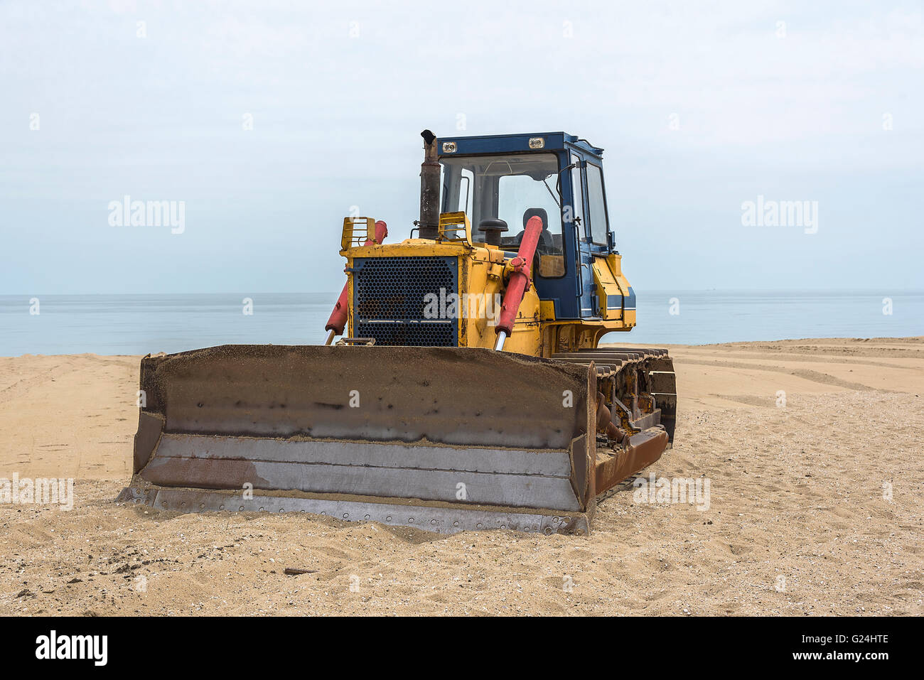 Vieux tracteur jaune sur une plage de la mer de sable. Banque D'Images