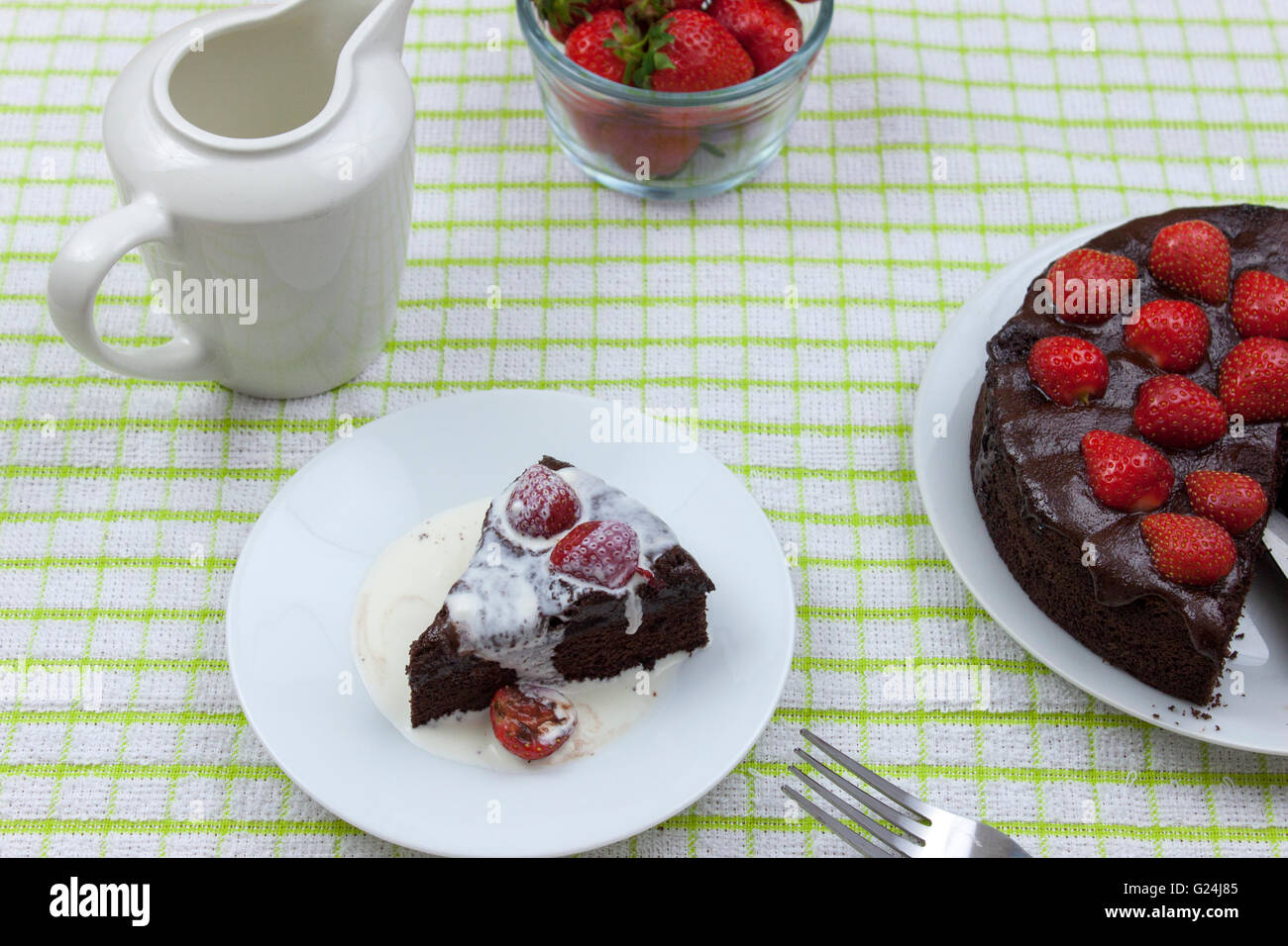 La crème fraîche couverte tranche de gâteau fondant au chocolat garnie de strawberrys sur un tableau par pays Banque D'Images