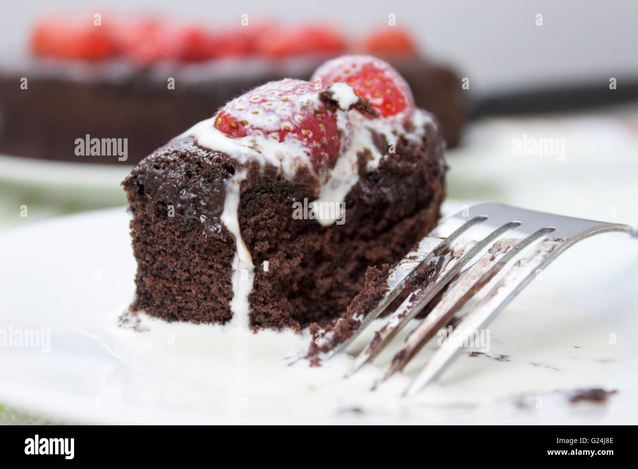 Tranche de gâteau fondant au chocolat garnie de fraise est couvert dans la crème fraîche Banque D'Images