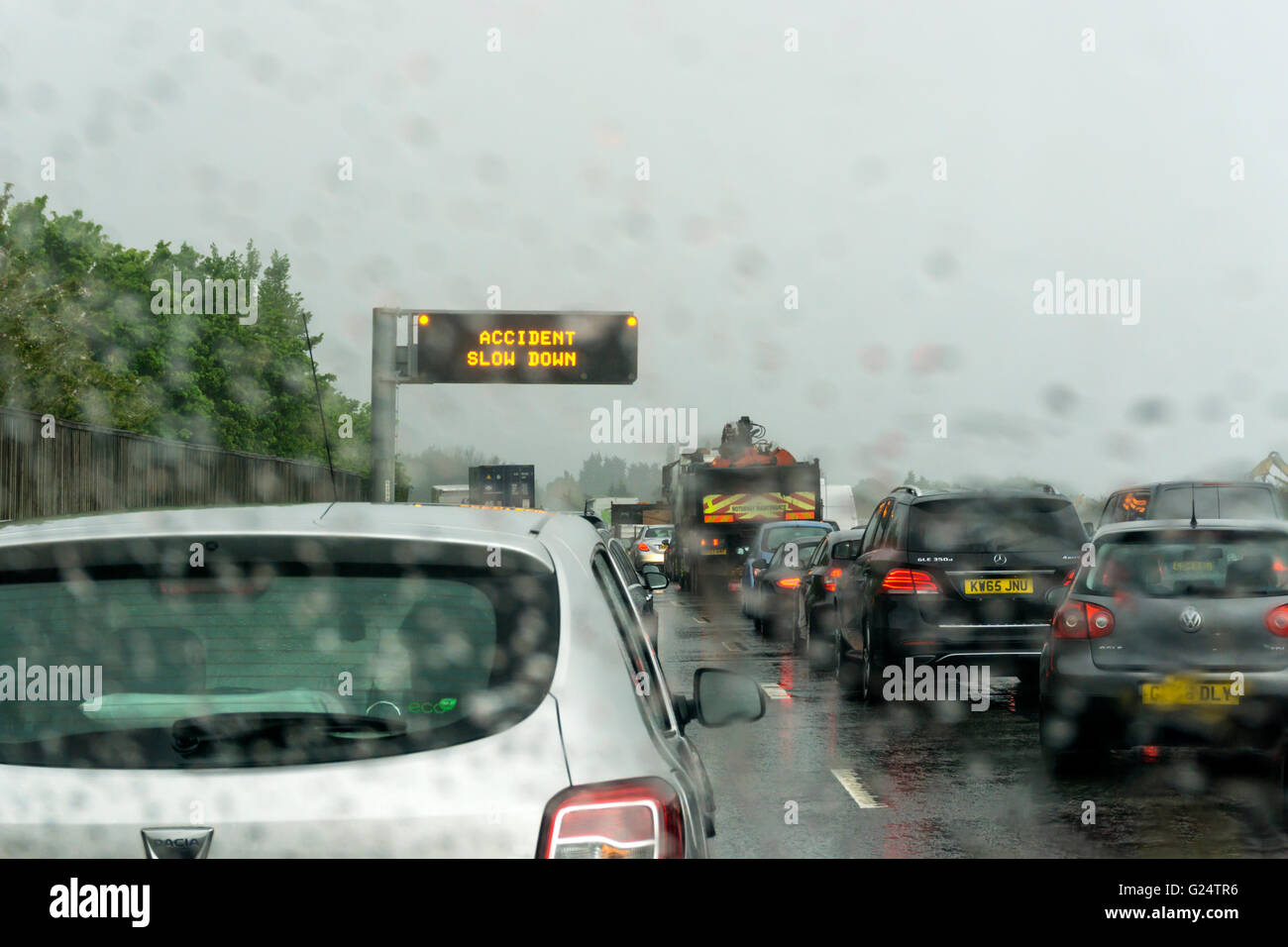 File d'attente de circulation sous la pluie sur l'A20 près de la jonction avec la M25. Panneau d'avertissement se lit Accident ralentir. Banque D'Images