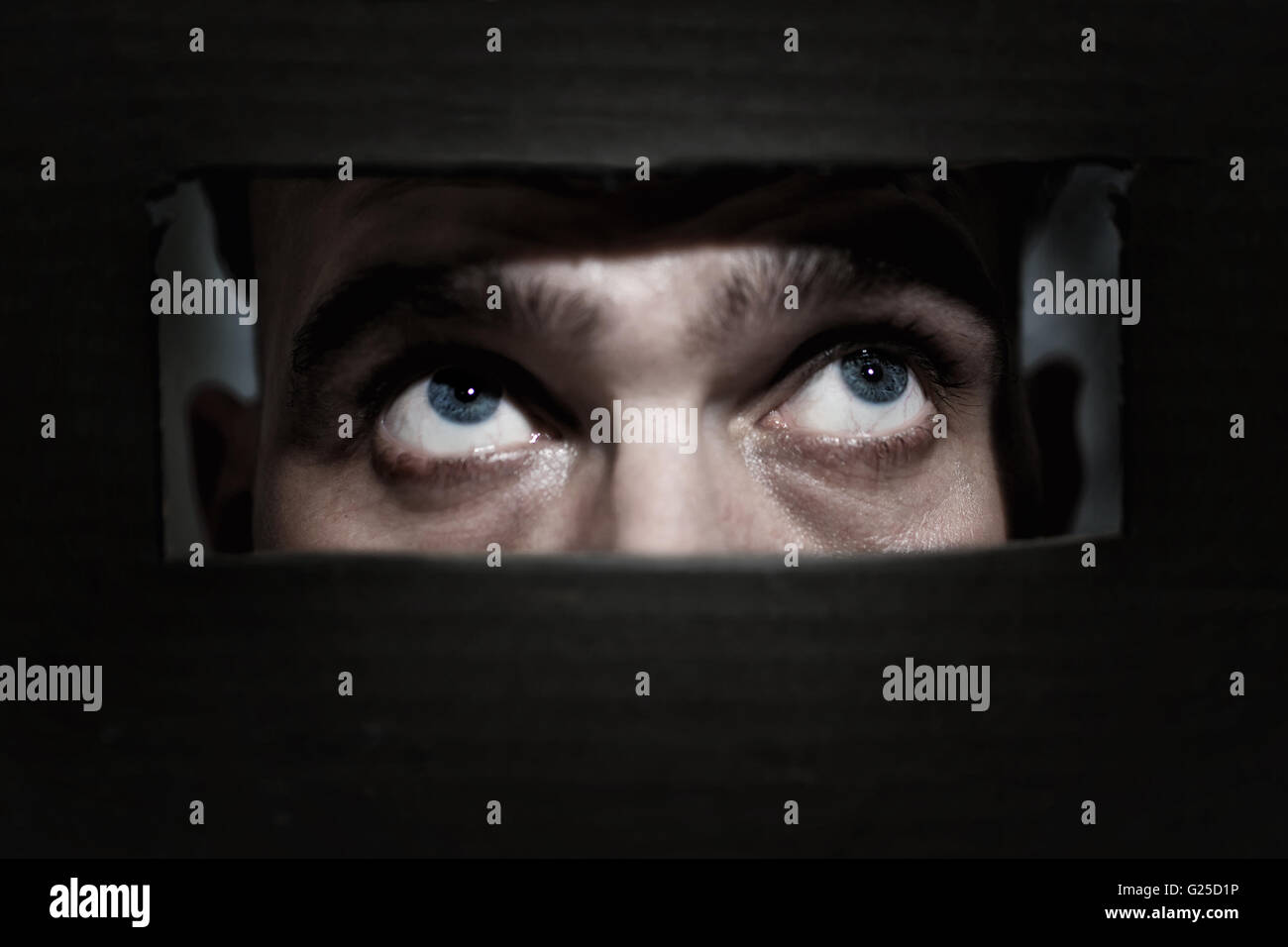 Les yeux des hommes à travers l'espionnage d'un trou dans le mur Banque D'Images