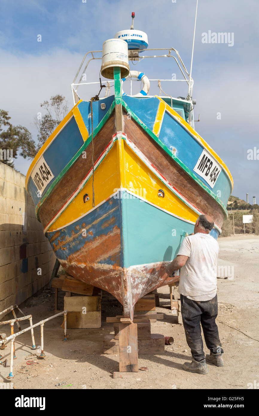 Man painting bateau de pêche traditionnel, Marsaxlokk, Malte Banque D'Images