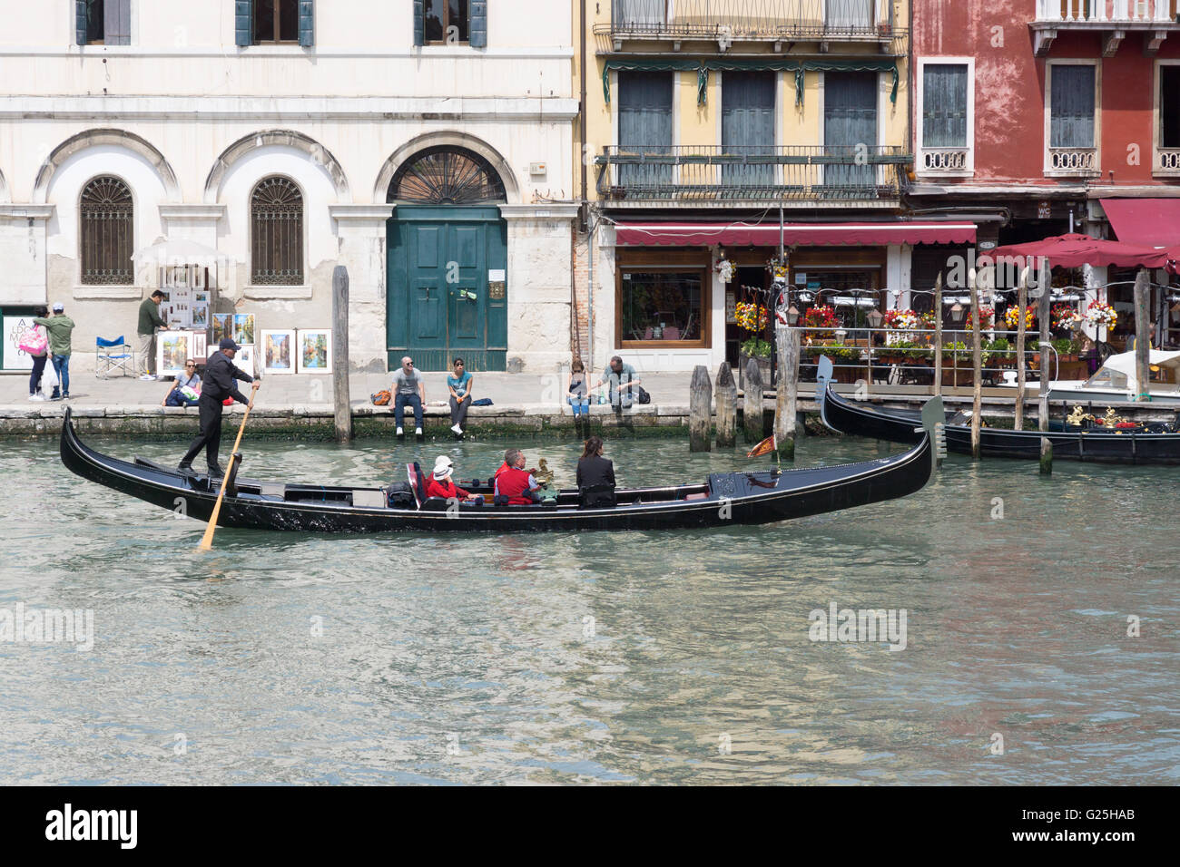 Les touristes assis dans une gondole vénitienne traditionnelle étant propulsés et dirigés par un gondolier avec un rame sur le Grand Canal, Venise, Italie Banque D'Images