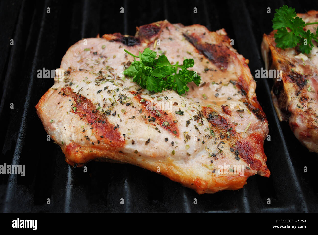Une côtelette de porc parfaitement cuit sur un gril garni de persil frais Banque D'Images