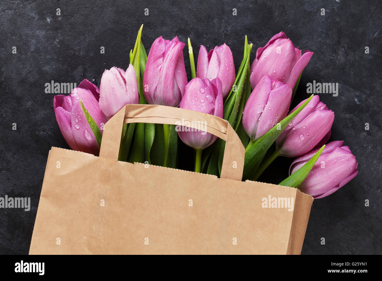 Fleurs tulipe violette fraîche sac de papier sur la table en pierre sombre. Vue d'en haut Banque D'Images