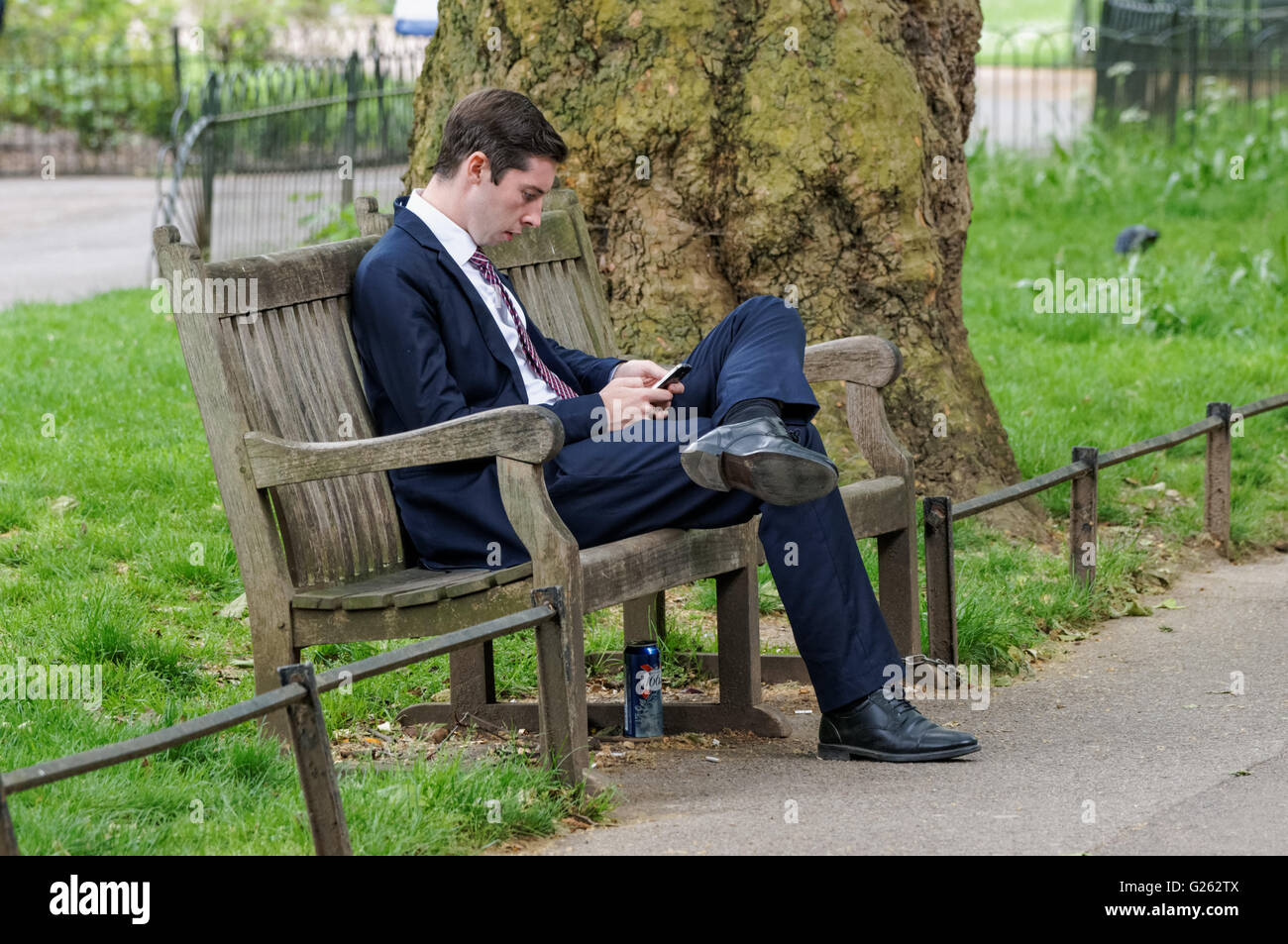 Jeune homme assis sur un banc à St James's Park, Londres Angleterre Royaume-Uni UK Banque D'Images