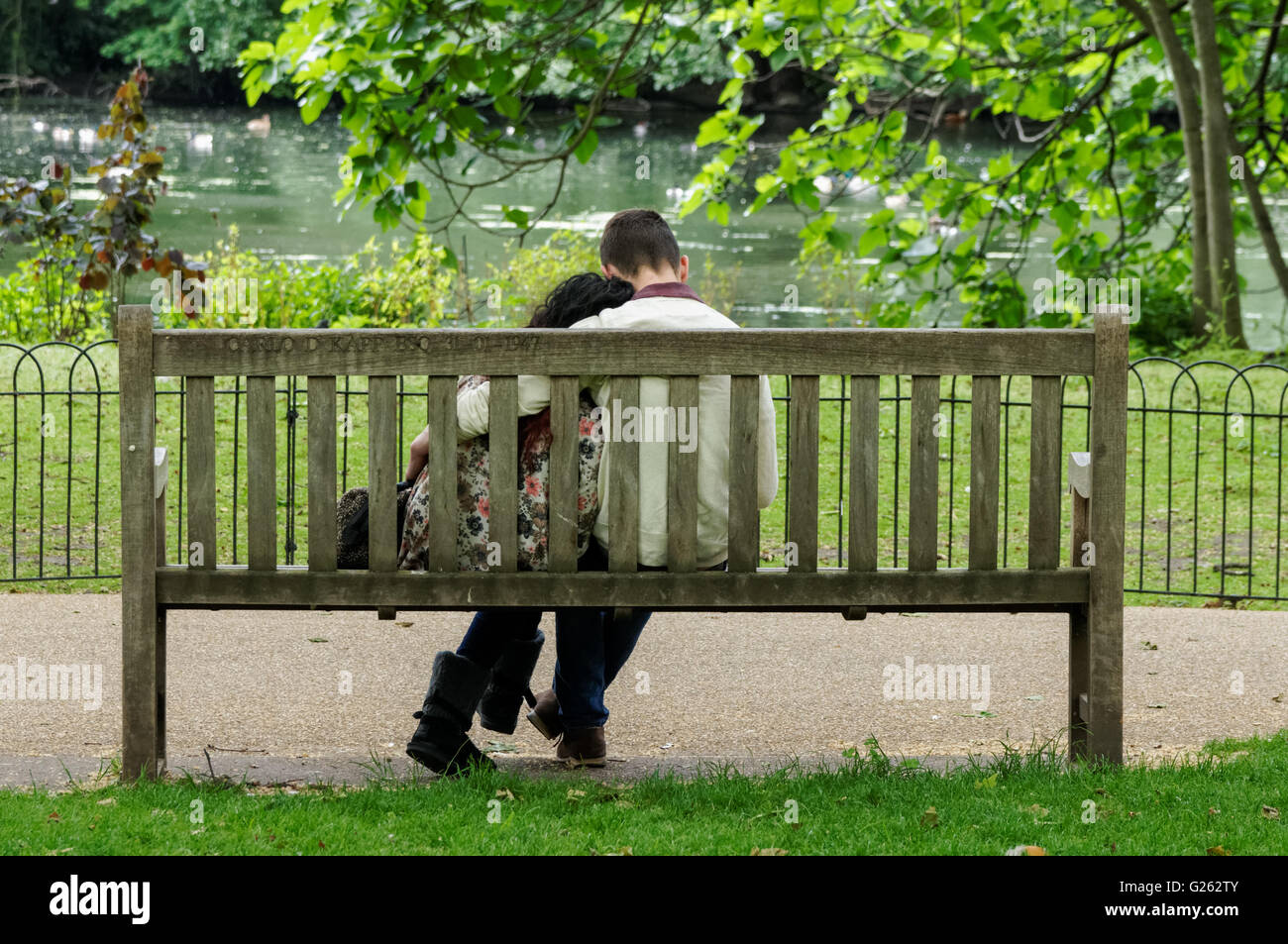 Jeune couple assis sur un banc à St James's Park, Londres Angleterre Royaume-Uni UK Banque D'Images