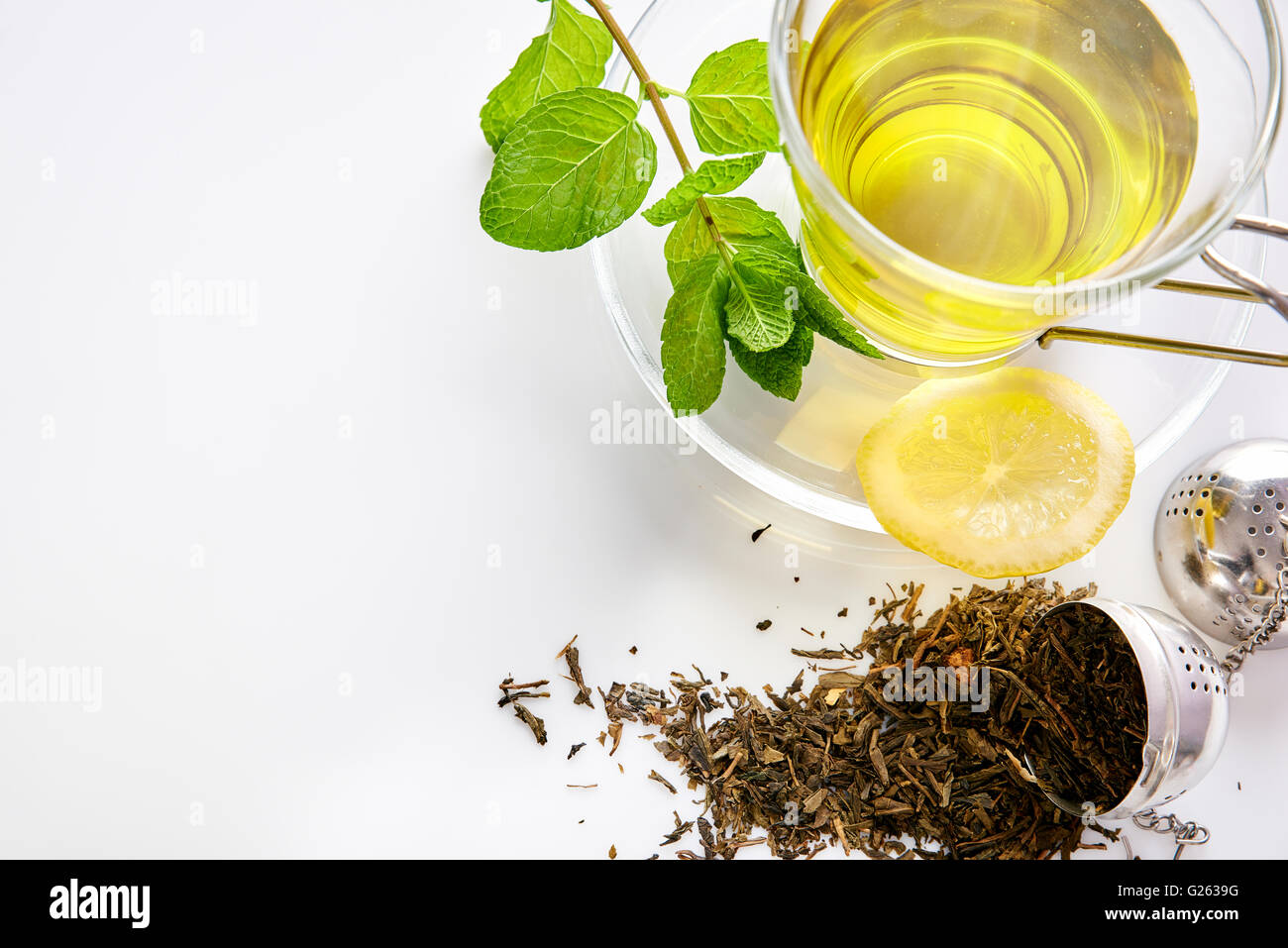 Tasse en verre de thé vert à la Menthe et citron, et crépine métallique sur une table dans le salon de près. Composition horizontale. Haut Banque D'Images