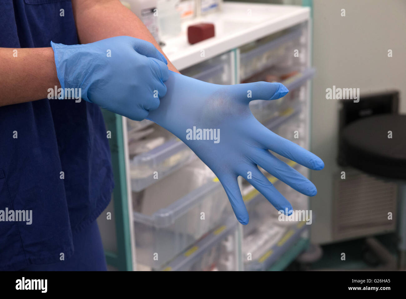 Un technicien de théâtre met des gants bleu stérile en vue d'une opération Banque D'Images