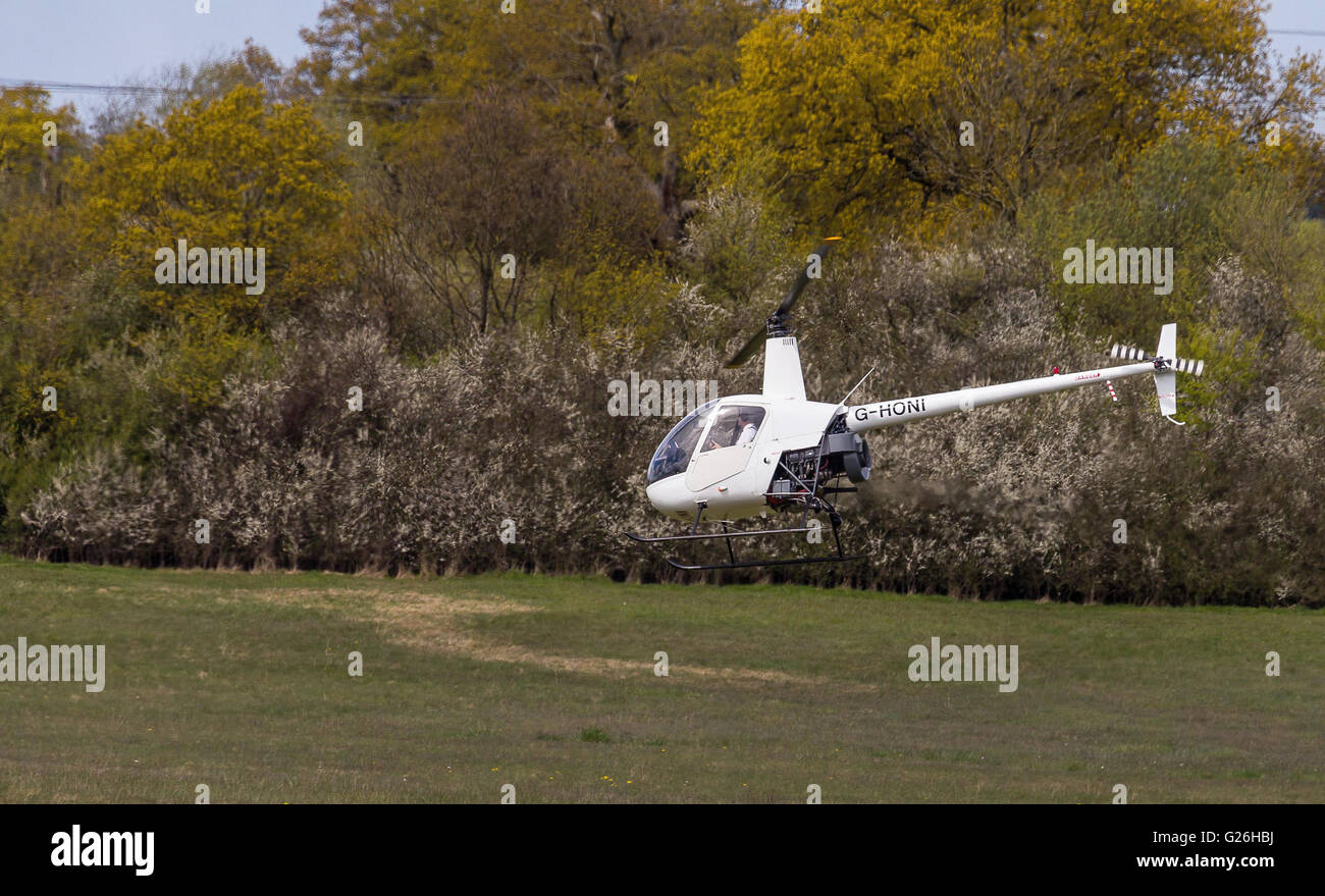 Un hélicoptère Robinson R22, G-HONI, volant bas, très près du sol à Elstree Airfield en Hertfordshire, Royaume-Uni Banque D'Images
