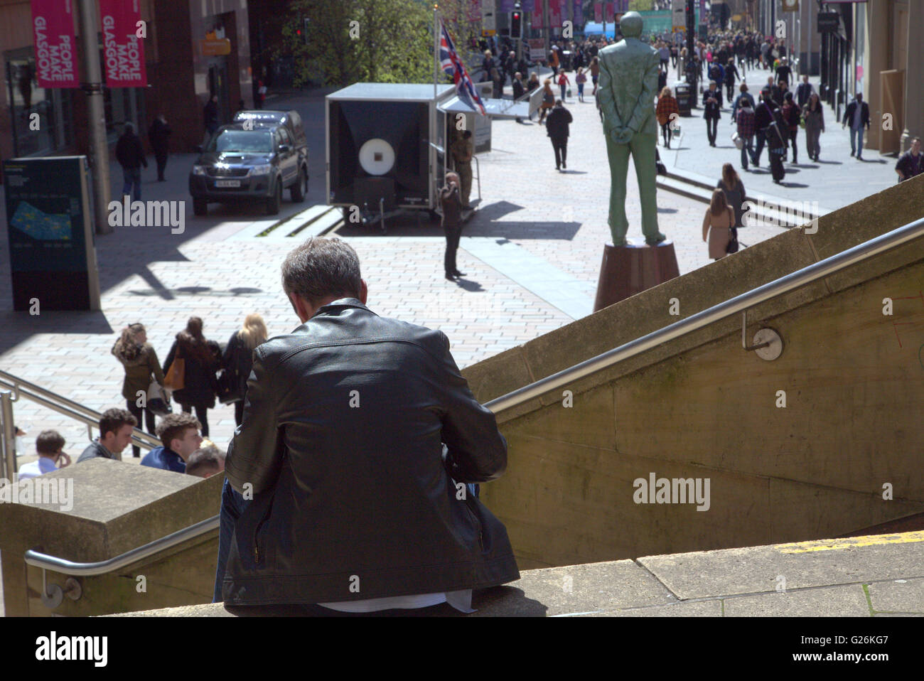 Homme assis sur les marches en haut de Buchanan Street, Glasgow, Scotland, UK. Banque D'Images