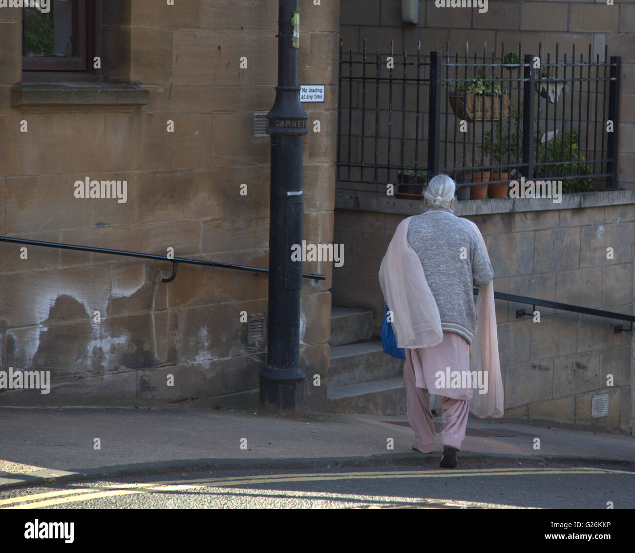 Vieille Femme Asiatique de marcher à travers la rue vue d'en haut, Glasgow, Ecosse, Royaume-Uni. Banque D'Images