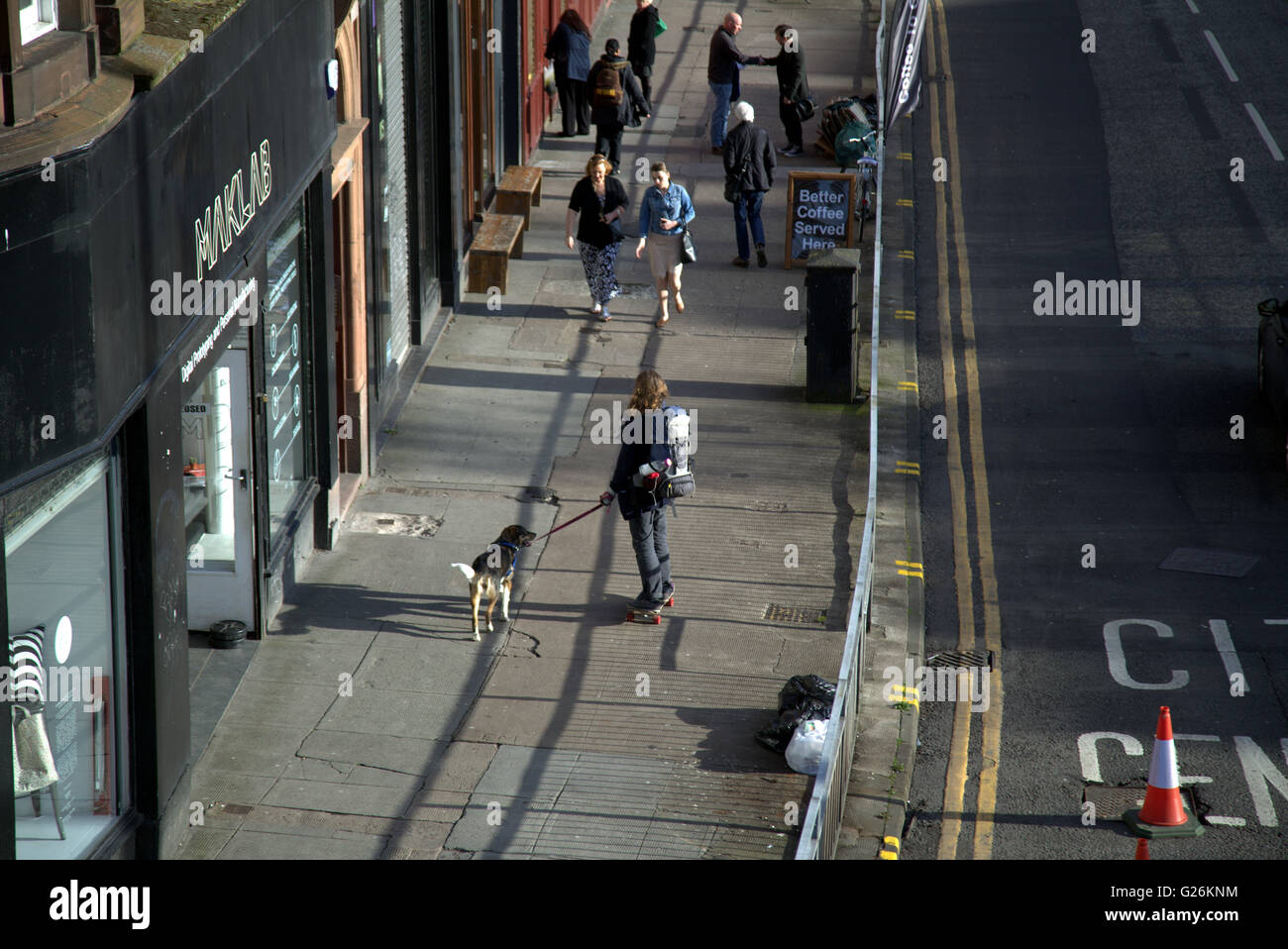 Femme sur planche chien marche sur la rue vue d'en haut, Glasgow, Ecosse, Royaume-Uni. Banque D'Images