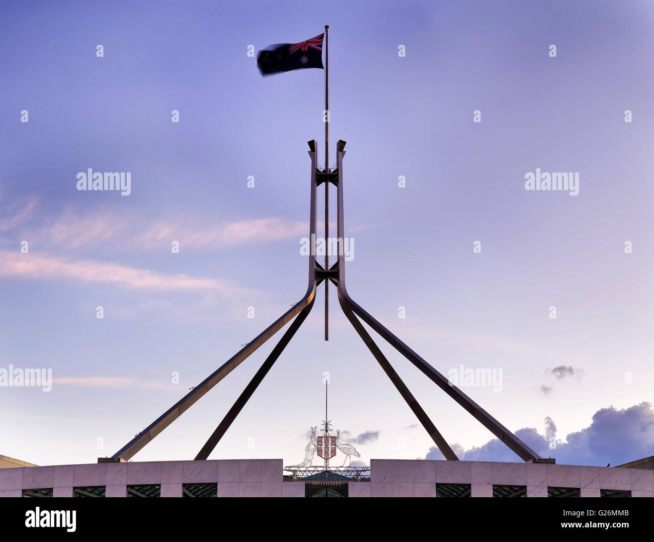 Drapeau national australien sur un flagpolle au sommet de la maison du parlement à Canberra, au coucher du soleil. Brandissant le drapeau est sur le vent. Banque D'Images