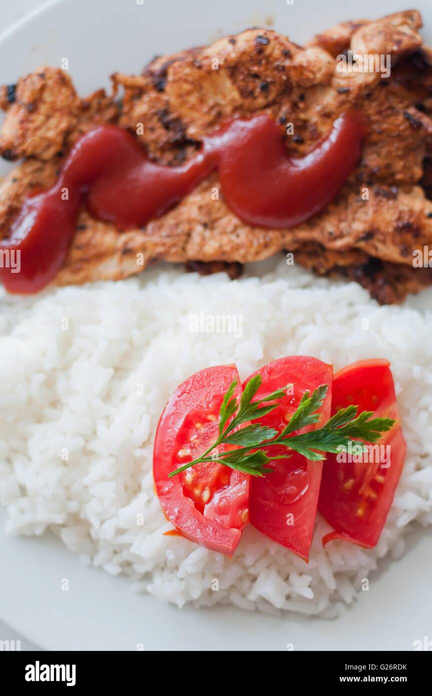 Steak de poulet dans un plat servi avec du riz et de la tomate en tranches. Photo verticale Banque D'Images