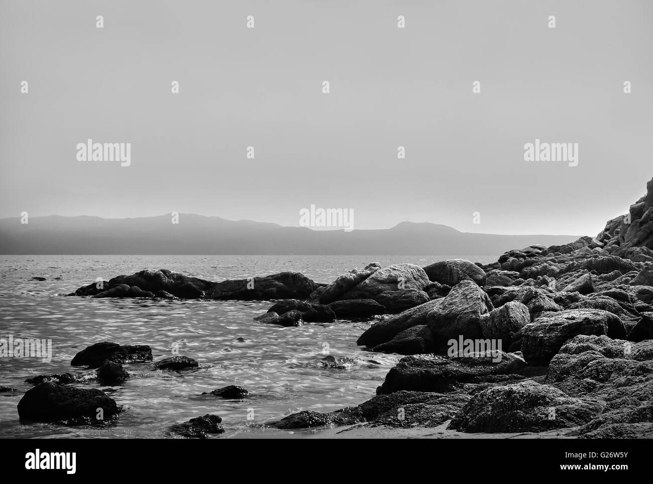 La photo artistique de roches par la mer en noir et blanc Banque D'Images