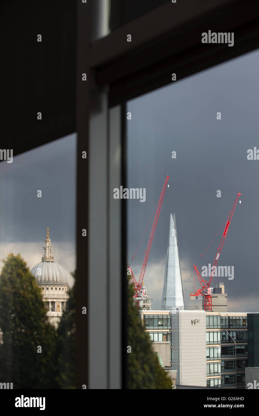 St Pauls Cathderal sur l'horizon avec vue sur les toits de la ville de Londres, et l'arrière de la pyramide de verre comme structure du Shard avec côtés verre brillants dans la lumière et peint rouge evning site construction de grues. Banque D'Images