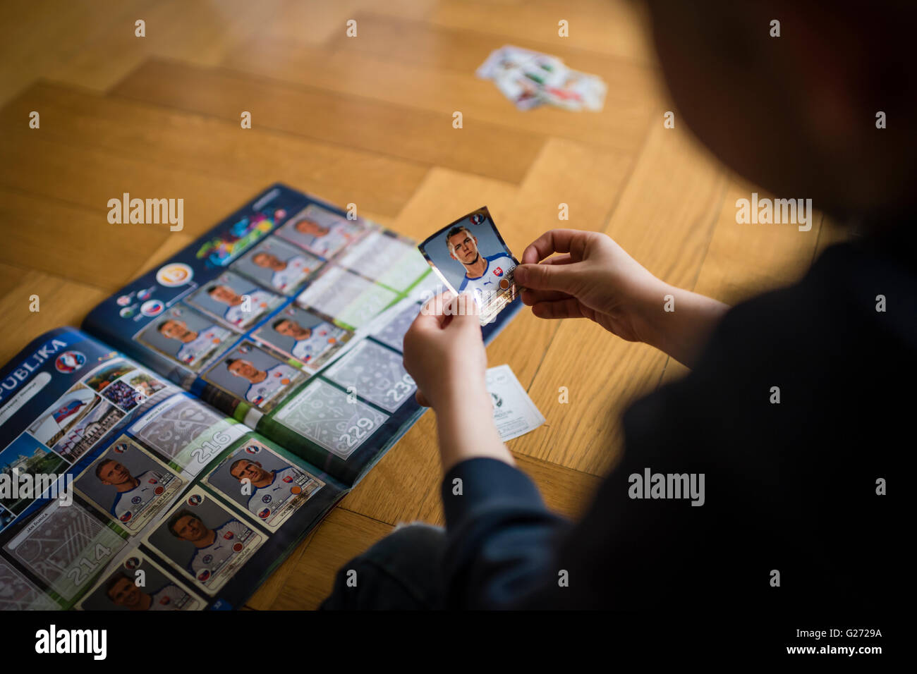 Un garçon de 8 ans est de coller l'UEFA Euro 2016 football Panini trading cards dans son album collection autocollant. Banque D'Images