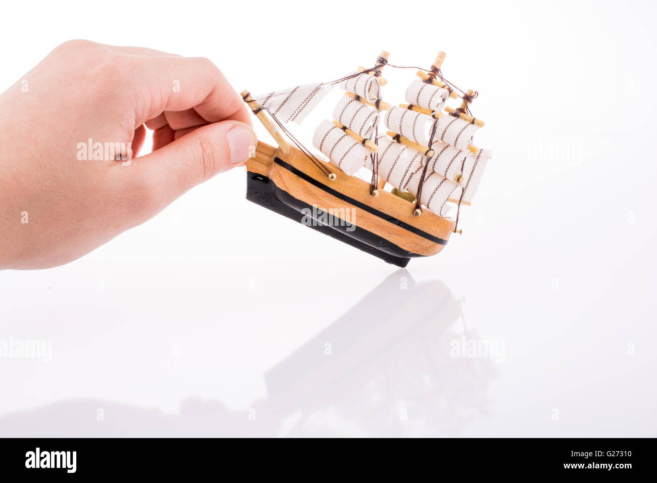 Part en contact avec un petit modèle voilier sur fond blanc Banque D'Images