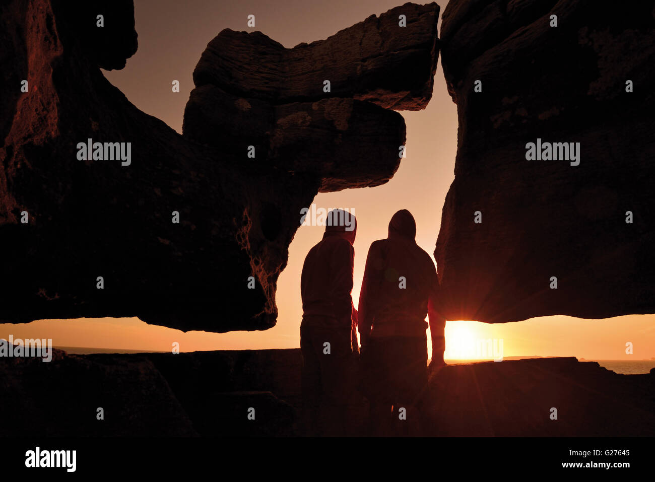 Portugal : Silhouette de deux personnes regardant le coucher du soleil panoramique avec curieux rock formation au Cap Carvoeiro Banque D'Images