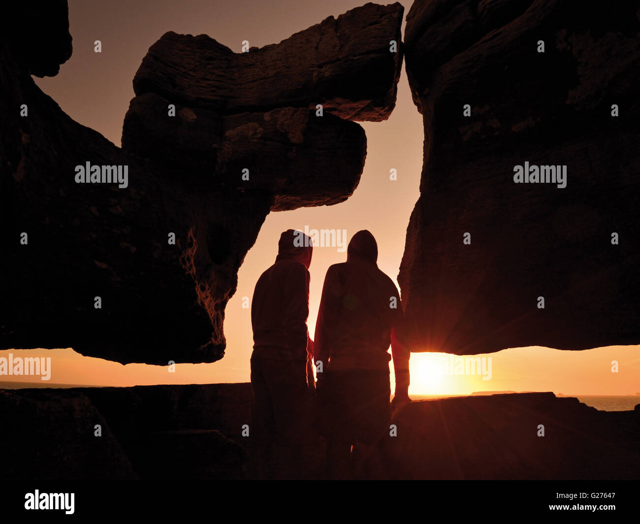 Portugal : Silhouette de deux personnes regardant le coucher du soleil panoramique avec curieux rock formation au Cap Carvoeiro Banque D'Images