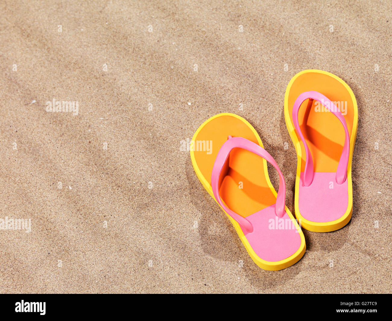 Une paire de tongs rose-orange allongé sur le sable Banque D'Images