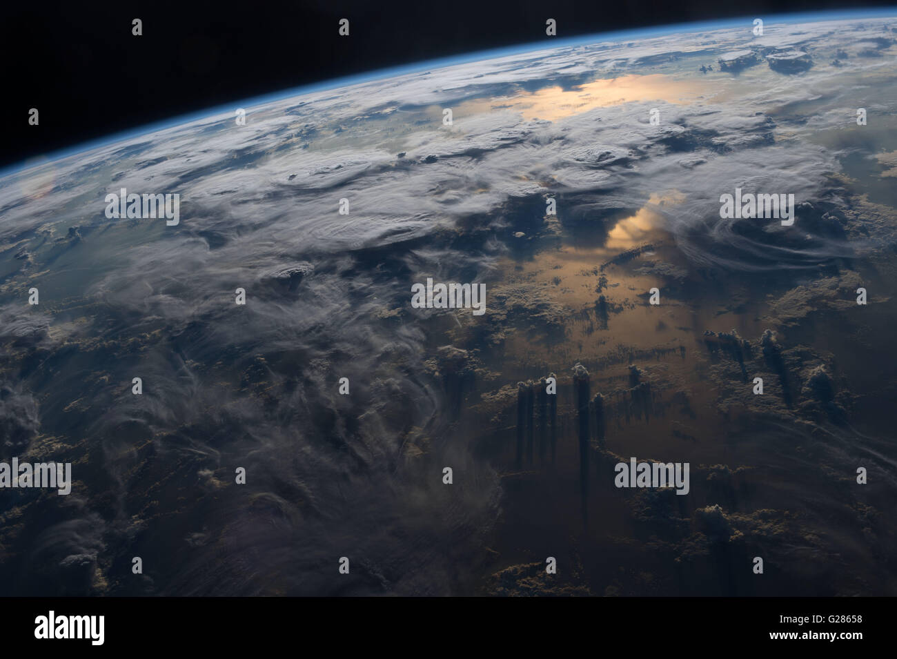 Voir des nuages, les orages et le coucher du soleil réfléchie par la Terre vue de la Station spatiale internationale. Banque D'Images