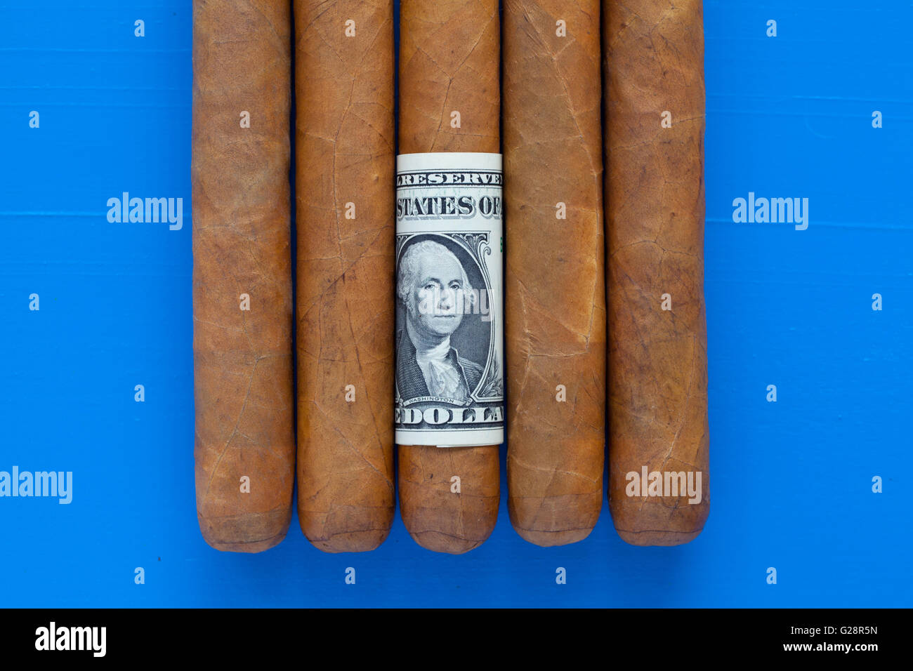 Détail de cigares cubains de luxe avec du dollar américain sur le bureau bleu Banque D'Images
