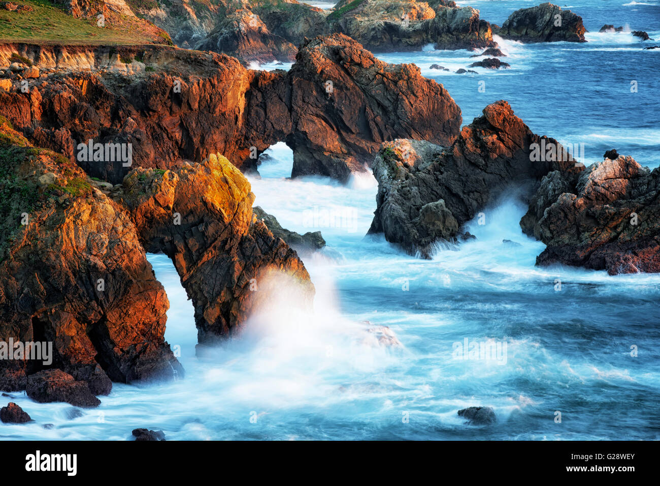 Lumière du soir baigne les vagues se brisant sur la côte sauvage de la Californie Big Sur. Banque D'Images