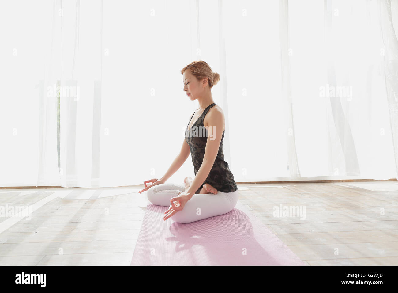 Les jeunes Japonais attrayante la pratique du yoga dans une salle aérée Banque D'Images