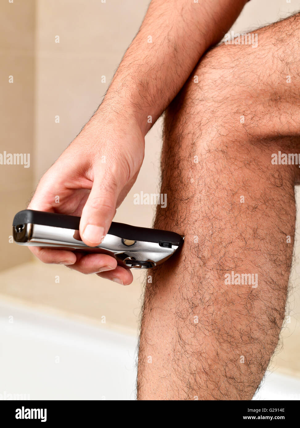 Libre d'un jeune homme de race blanche coupe des poils de ses jambes avec une tondeuse électrique Banque D'Images