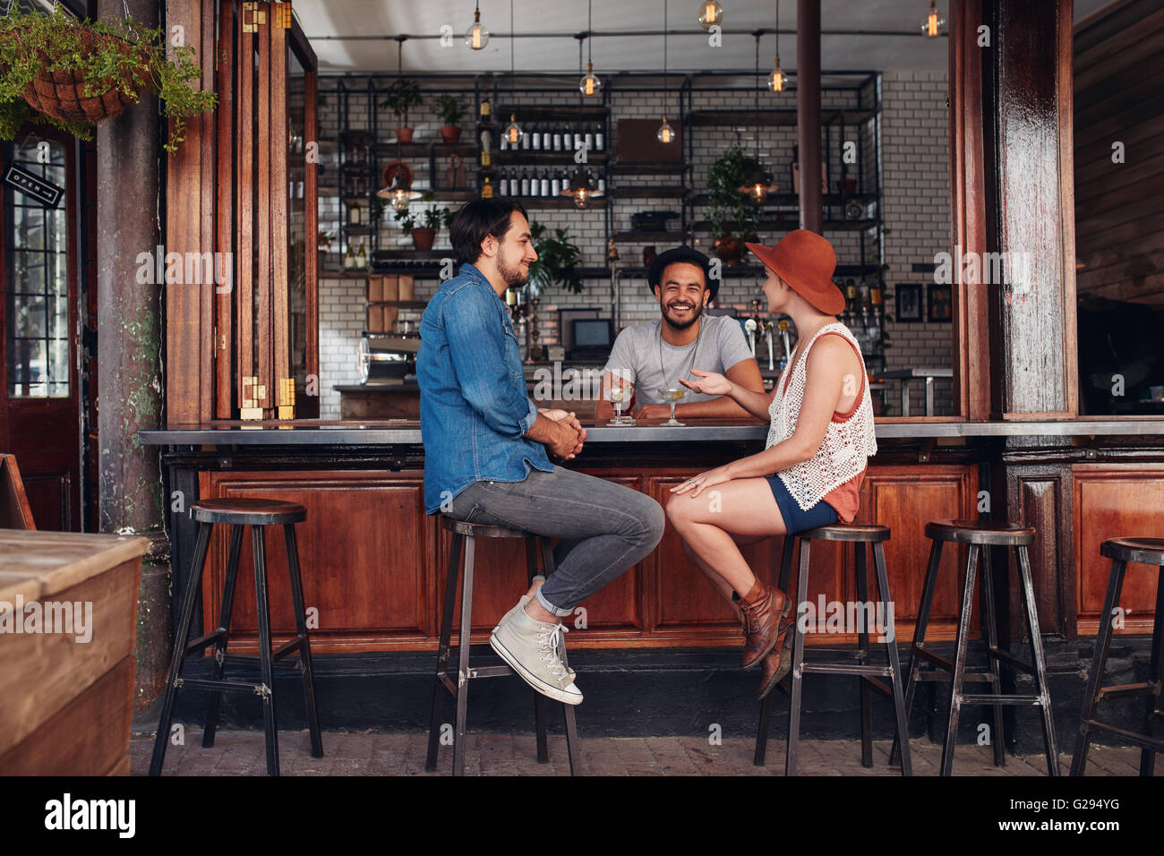 Groupe de jeunes gens assis dans un café et parler. Les jeunes hommes et de femmes réunis au café table. Banque D'Images