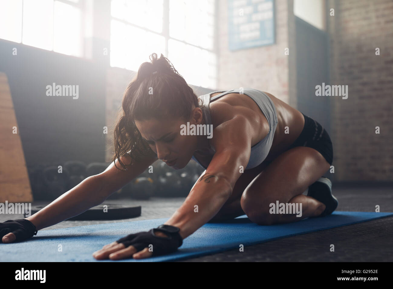Shot of a young woman doing yoga sur le plancher du gymnase. Femelle doing stretching musculaire à l'entraînement d'un club de santé. Banque D'Images