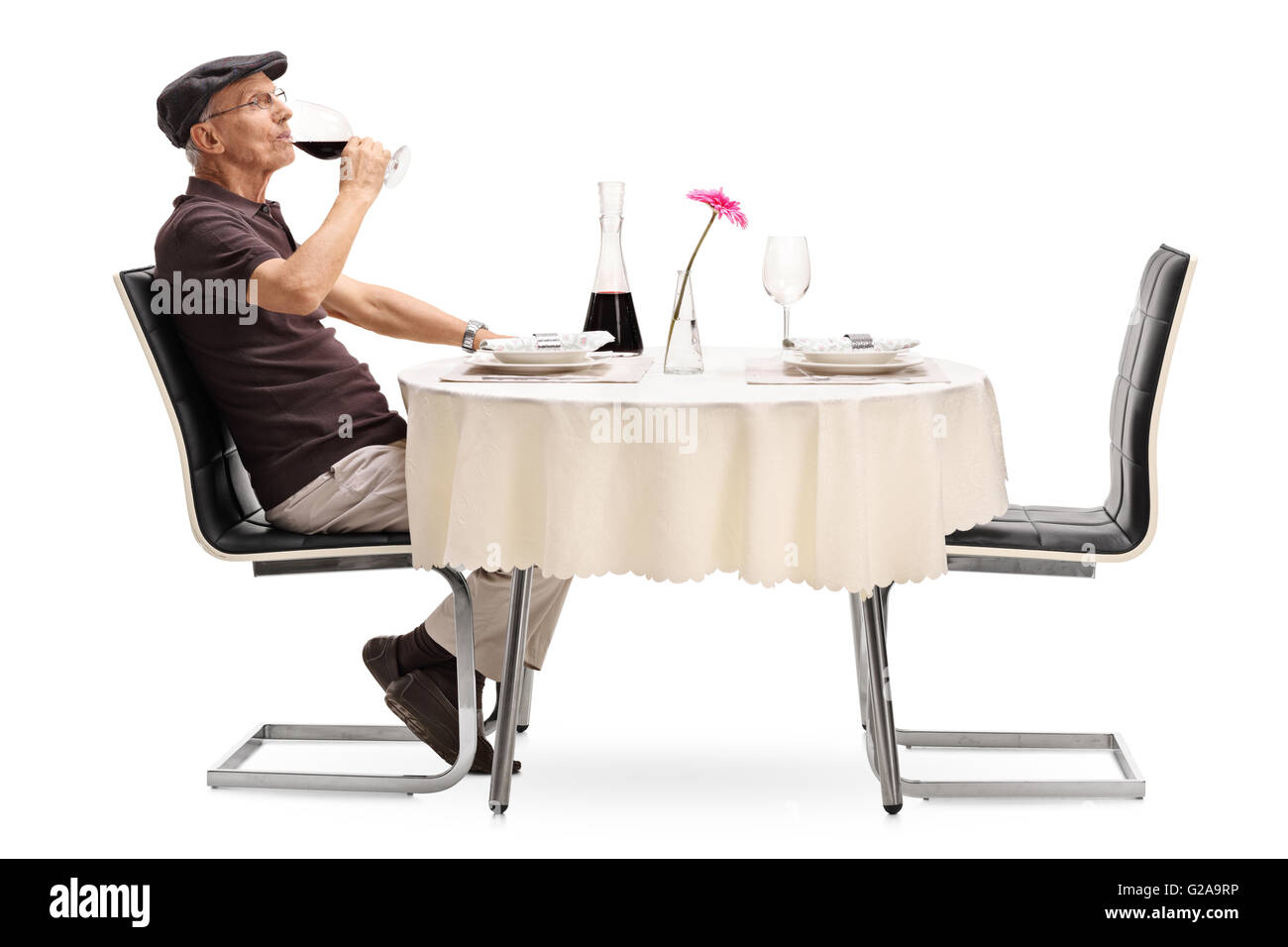 Représentant principal de boire du vin rouge et en attente de son jour assis à une table à manger isolé sur fond blanc Banque D'Images